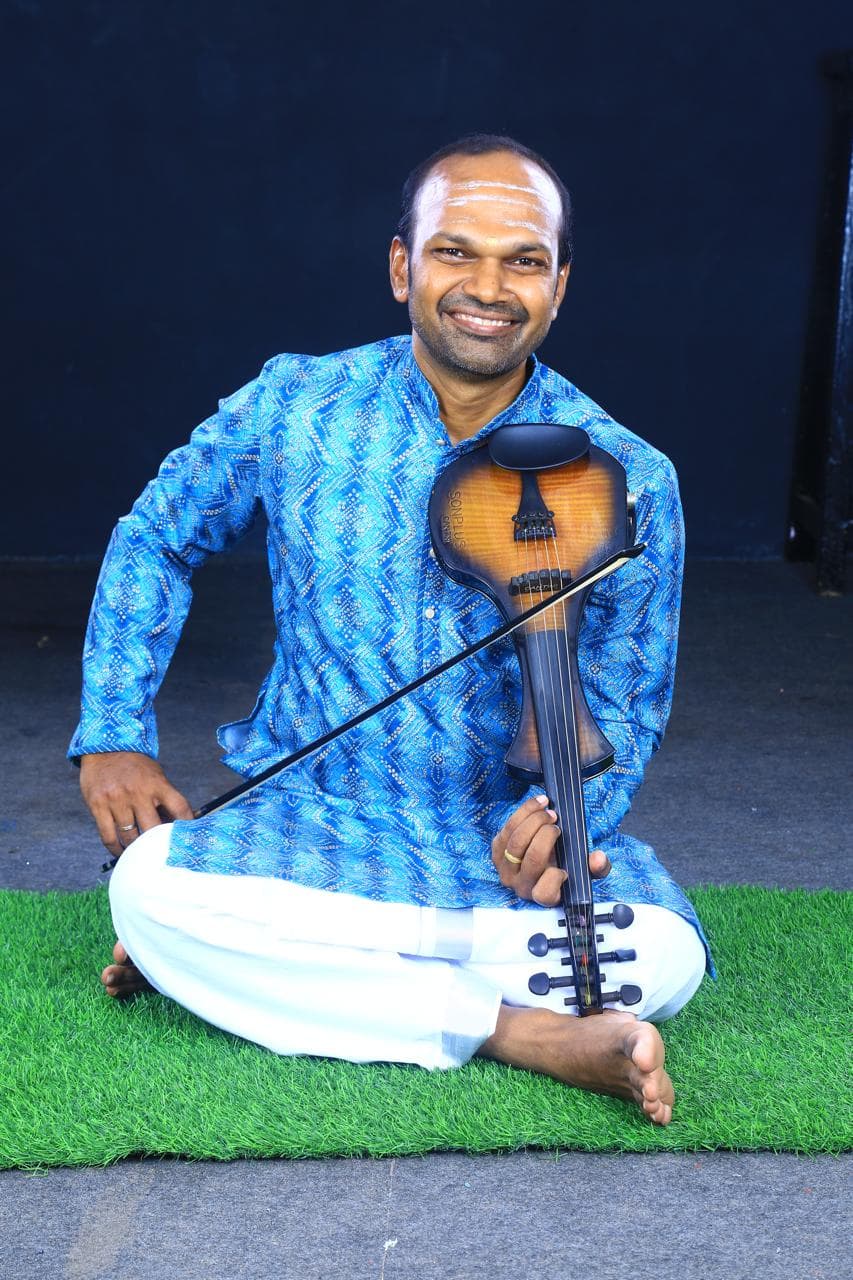 Violin Suka Pavalan seated with violin, stage portrait